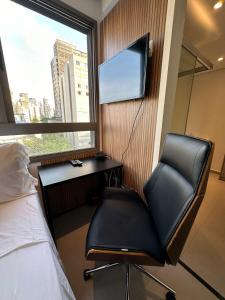 a bedroom with a desk and a chair and a television at MARCOLINI - Flat em frente ao Allianz Parque in Sao Paulo