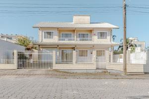 a white house with a fence in front of it at APTO Schmitt 01 - 500m praia wifi in Palhoça