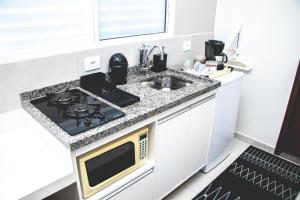 een witte keuken met een fornuis en een wastafel bij Kitnet prox a UNIFEI com Wi-Fi em Itajuba MG in Itajubá