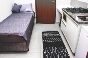 una pequeña cocina con cama y lavabo en una habitación en Kitnet prox a UNIFEI com Wi-Fi em Itajuba MG en Itajubá