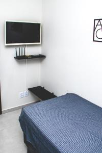 um quarto com uma cama e uma televisão na parede em Kitnet prox a UNIFEI com Wi-Fi em Itajuba MG em Itajubá