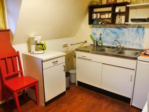 eine kleine Küche mit einer Spüle und einem roten Stuhl in der Unterkunft Ferienwohnung Unter den Linden in Rietberg