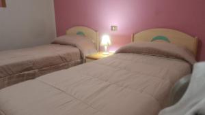 two beds in a room with pink walls at Casa Fiore in Cerreto di Spoleto