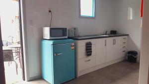 a microwave on top of a blue refrigerator in a kitchen at Nights on Broadway - The APARTMENT in Matamata