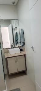 een badkamer met een wastafel en een spiegel bij Suíte em Cobertura, Não é a cobertura toda, somente suíte e piscina in Bombinhas