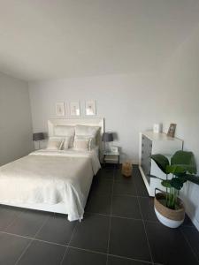 una camera con un letto bianco e una pianta in vaso di Paraiso a Villaverde