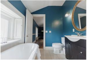 a bathroom with a white tub and a blue wall at The Hamilton Hoppin House in Middletown