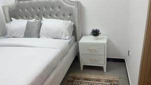 een slaapkamer met een wit bed en een nachtkastje bij Starrot in Nairobi