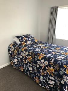 a bedroom with a bed with a blue floral bedspread at Nights on Broadway - THE HOUSE in Matamata