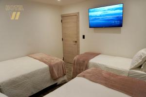 a room with two beds and a television on the wall at HOTEL W Santa Marta in Gaira