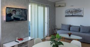 a living room with a couch and a tv on a wall at Villa Blue Oasis in Kaštela