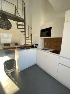 a kitchen with white cabinets and a staircase at Suite One Löwengrube in Munich