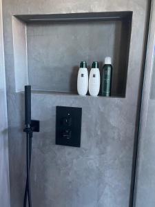 a shelf with three shampoo bottles on a wall at Suite One Löwengrube in Munich
