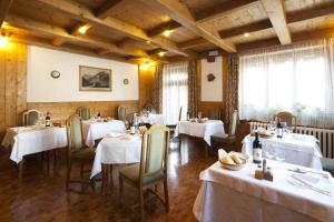 une salle à manger avec des tables et des chaises blanches dans l'établissement Hotel Bellaria - Cortina d'Ampezzo, à Cortina dʼAmpezzo