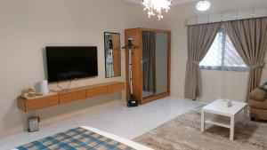sala de estar con TV de pantalla plana en la pared en شقة مفروشة ليالي العروبة متميزة مؤثثة بأثاث أنيق ومريح, en Riad
