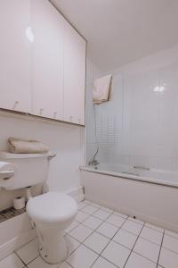 a white bathroom with a toilet and a bath tub at Smithfield square Nest in Dublin