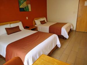 a room with two beds in a hotel room at Hotel Plaza Morelos in Toluca