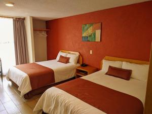 2 camas en una habitación de hotel con paredes de color naranja en Hotel Plaza Morelos, en Toluca