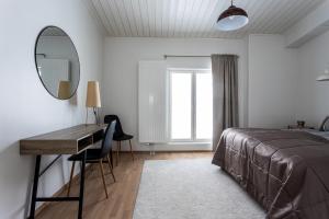 Schlafzimmer mit einem Bett, einem Schreibtisch und einem Spiegel in der Unterkunft Ainutlaatuinen ullakkohuoneisto ydinkeskustassa in Kuopio