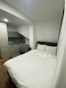 uma grande cama branca num pequeno quarto em President Kopaonik Apartman l/ll 