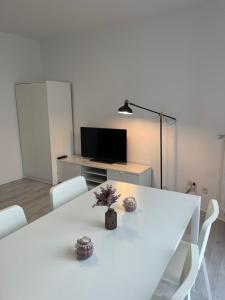 City Apartment am Rhein Bonn في بون: غرفة طعام بيضاء مع طاولة بيضاء وكراسي بيضاء