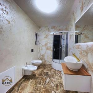 ein Badezimmer mit zwei Waschbecken, einem WC und einer Dusche in der Unterkunft Vila Costi in Câmpina
