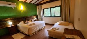 a room with two beds and a green wall at Sítio Costão da Fortaleza - Canyons do Brasil in Praia Grande