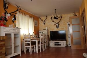 sala de estar con mesa y TV en Casa en sierra de gredos piscina privada, en La Adrada