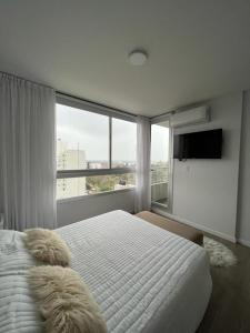a bedroom with a white bed and a large window at Departamento en San Lorenzo in San Lorenzo