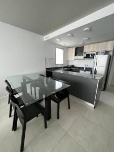 uma cozinha com uma mesa de vidro e cadeiras pretas em Departamento en San Lorenzo em San Lorenzo