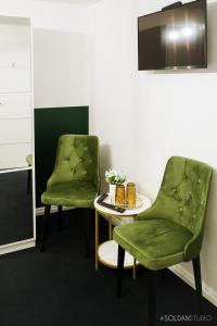 - deux chaises vertes et une table dans une pièce dans l'établissement La Codrii Cajvanei, 