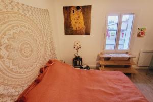 um quarto com uma cama com um cobertor laranja e uma janela em Pretty haven of peace with terrace em Avignon
