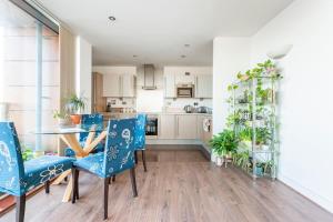 una cucina e una sala da pranzo con sedie blu e tavolo di London Skylineviews 2 bed 2 bath flat near Canary Wharf, o2 & Excel a Londra