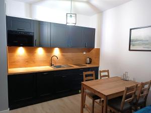 uma cozinha com um lavatório e uma mesa de madeira com uma sala de jantar em AlfaHome Manufaktura em Lódź