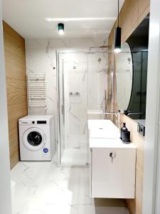 uma casa de banho com uma máquina de lavar roupa e um chuveiro em AlfaHome Manufaktura em Lódź