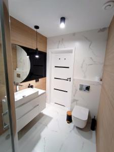 uma casa de banho branca com um lavatório e um WC em AlfaHome Manufaktura em Lódź