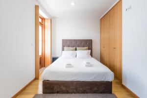 um quarto com uma cama grande e lençóis brancos em GuestReady - Daisy Boutique no Porto