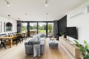 a living room with a couch and a tv and a table at Kalwa Lake House - dom nad jeziorem z prywatnym pomostem i jacuzzi oraz sprzętem wodnym in Pasym