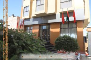 um edifício com bandeiras vermelhas à frente dele em MH HOTEL LA CASA em Laayoune