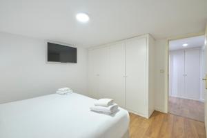 Dieses weiße Zimmer verfügt über ein Bett und einen TV. in der Unterkunft Lovely Apartments - Alójate en el corazón de Madrid in Madrid