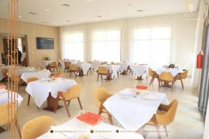 uma sala de jantar com mesas e cadeiras brancas em MH HOTEL LA CASA em Laayoune