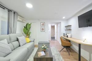 ein Wohnzimmer mit einem Sofa und einem Schreibtisch in der Unterkunft Lovely Apartments - Alójate en el corazón de Madrid in Madrid
