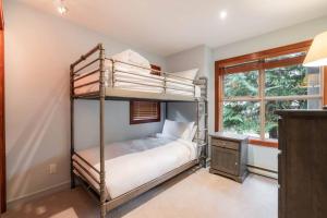 a bedroom with two bunk beds and a window at Treeline by Outpost Whistler in Whistler