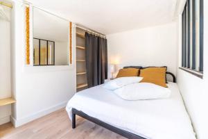um quarto com uma cama com lençóis brancos e almofadas laranja em Appartement entier haut de gamme em Bordeaux