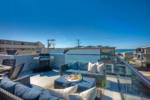 a balcony with a couch and a table on a roof at NEW Luxury Beach Home I 3BR I Balcony I Firepit in San Diego