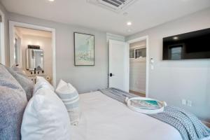 a bedroom with a white bed and a tv at Luxury Ocean Oasis 3BR I Balcony I Firepit in San Diego