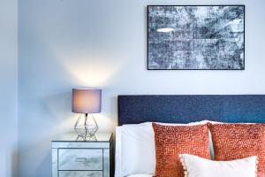 a bedroom with a bed with a lamp on a night stand at Artsy Serviced Apartments - Victoria in London