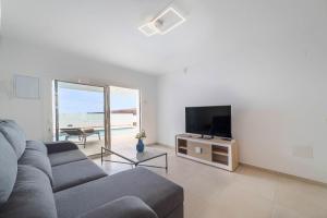uma sala de estar com um sofá e uma televisão de ecrã plano em Villa Garoé em Playa Quemada