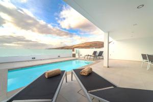 uma casa com piscina e duas cadeiras em Villa Garoé em Playa Quemada