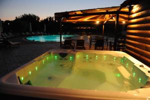 a jacuzzi tub with green lights next to a pool at Tsokas Hotel in Finikounta